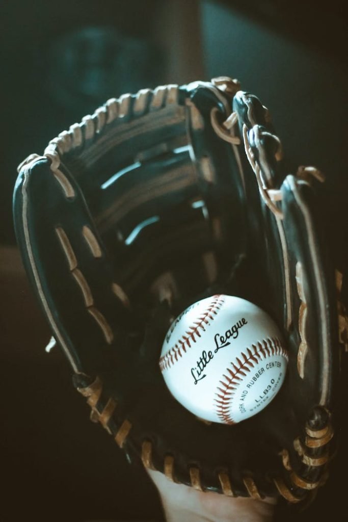 baseball-glove-and-ball-2868705 Close-up of a classic leather baseball glove holding a Little League ball, showcasing sports equipment details.